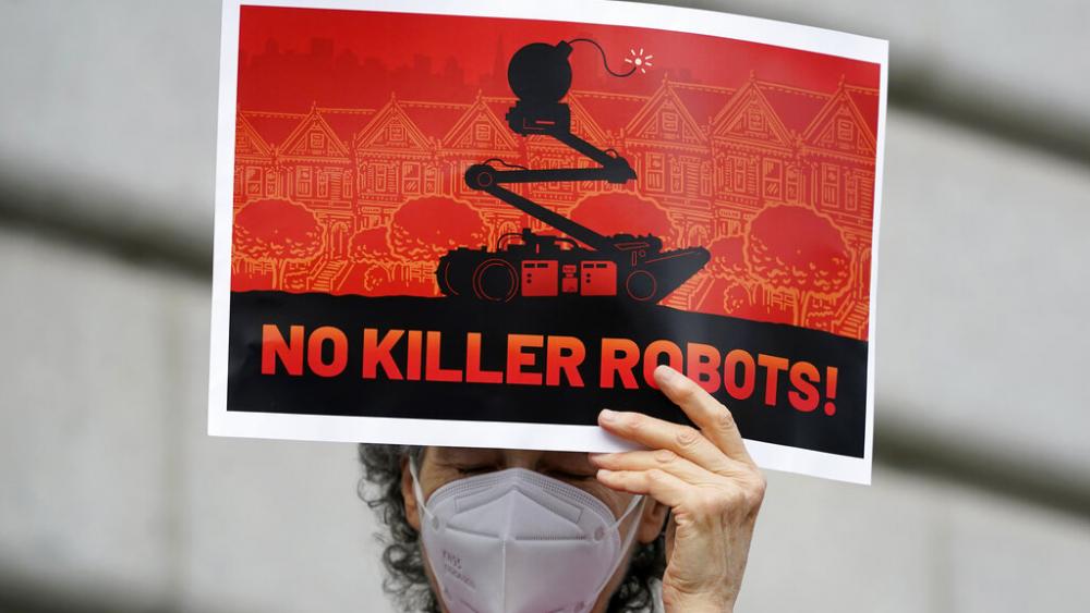 A woman holds up a sign while taking part in a demonstration about the use of robots by the San Francisco Police Department outside of City Hall in San Francisco, Monday, Dec. 5, 2022. 