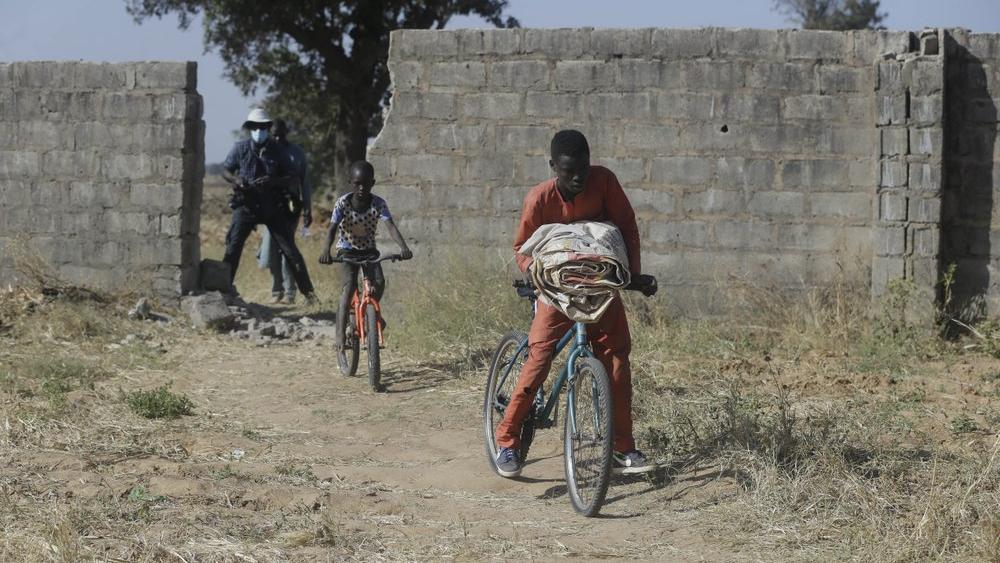 Children ride on bicycles past a wall broken by Boko Haram who kidnapped students from their school (AP Photo/Sunday Alamba)