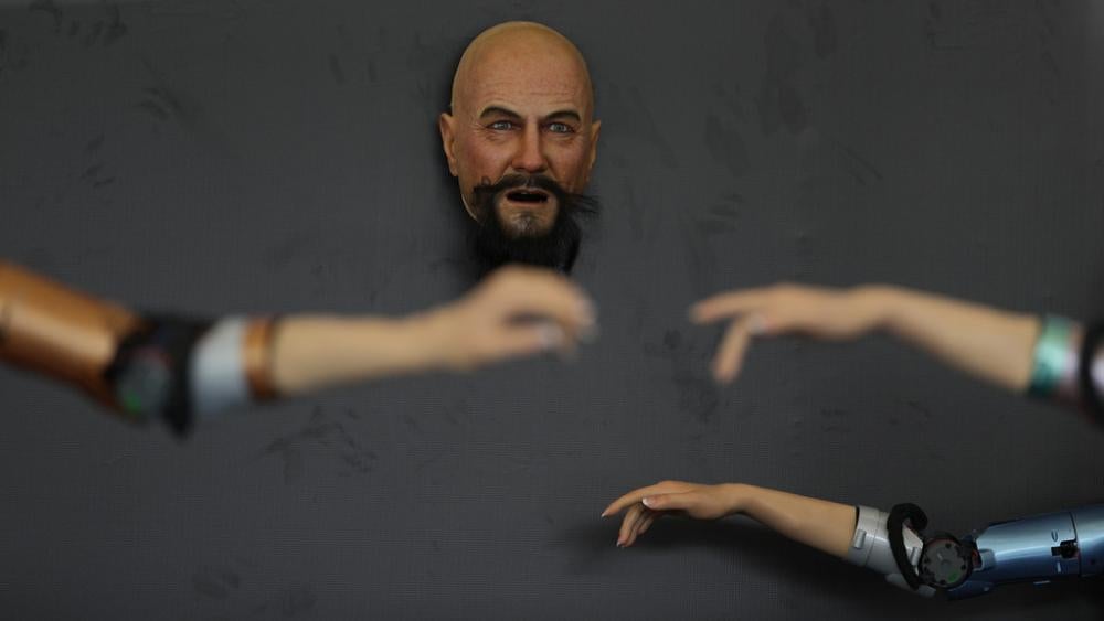 A robot face capable of mimicking human like expressions is displayed near robotic arms at the annual World Robot Conference at the Beijing Etrong International Exhibition and Convention Center in Beijing, Wednesday, Aug. 16, 2023. (AP Photo/Ng Han Guan)