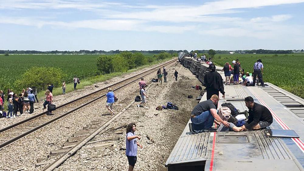 In this photo provided by Dax McDonald, an Amtrak passenger train lies on its side after derailing near Mendon, Mo., on Monday, June 27, 2022. (Dax McDonald via AP)