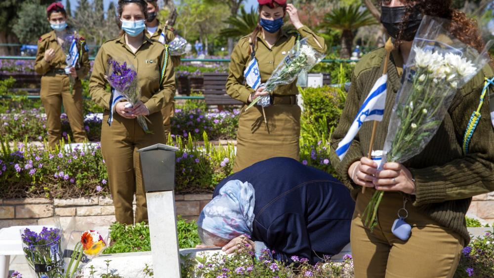 Georgia Gis, madre del soldado israelí Yitzhak Gis, besa su tumba mientras los soldados israelíes se paran cerca, antes del día conmemorativo del país para los soldados caídos y las víctimas de los ataques.  Foto AP.