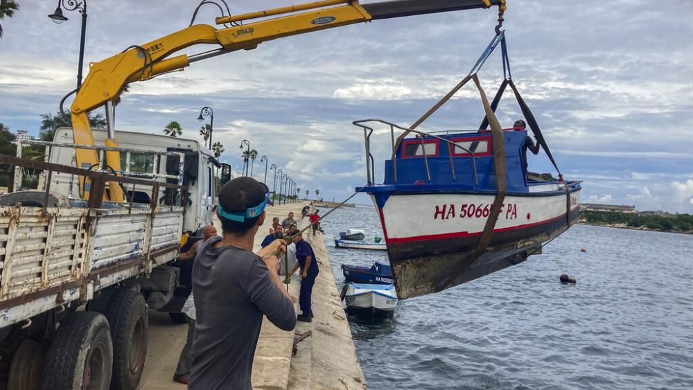 Workers remove a boat from the water in the bay of Havana, Cuba, Monday, Sept. 26, 2022. Hurricane Ian was growing stronger as it approached the western tip of Cuba on a track to hit the west coast of Florida as a major hurricane as early as Wednesday. (A