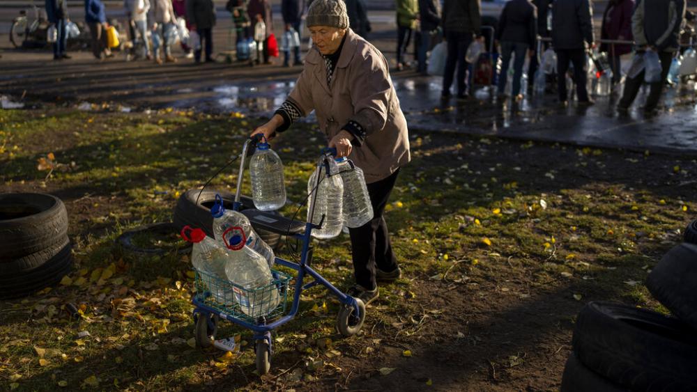 Catherine, 75, pushes her walker loaded with plastic bottles after refilling them in a tank, in the center of Mykolaiv, Monday, Oct. 24, 2022.  (AP Photo/Emilio Morenatti)