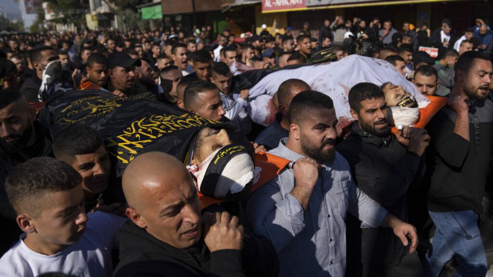 Palestinian mourners carry the bodies of Naeem Jamal Zubaidi, 27, left and Mohammad Ayman Saadi, 26, covered with flags of the Islamic Jihad Movement, during their funeral in the West Bank city of Jenin, Thursday, Dec. 1, 2022. (AP Photo/Nasser Nasser)