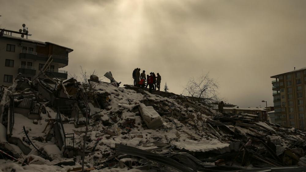 People try to reach people trapped under the debris of a collapsed building in Malatya, Turkey, Tuesday, Feb. 7, 2023. (AP Photo/Emrah Gurel)