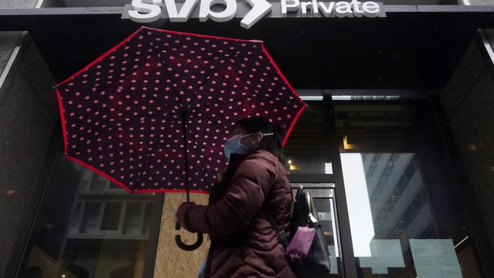 A pedestrian carries an umbrella while walking past a Silicon Valley Bank Private branch in San Francisco, Tuesday, March 14, 2023. (AP Photo/Jeff Chiu)