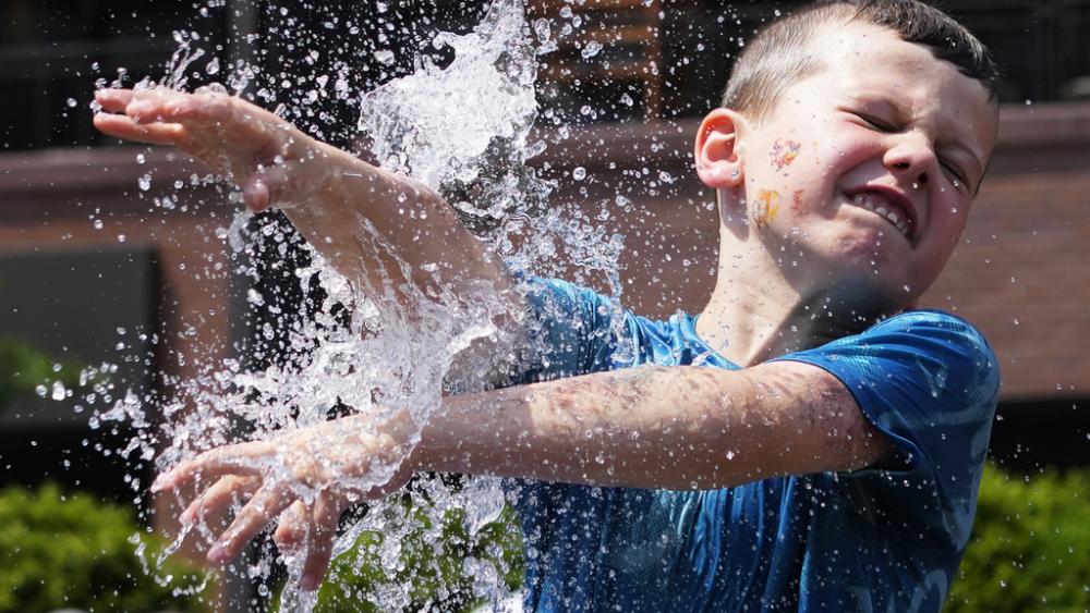 A boy cools off at a fountain outside Wrigley Field before a baseball game between the Chicago Cubs and St. Louis Cardinals as hot weather descends upon the Chicago area Sunday, June 16, 2024. (AP Photo/Nam Y. Huh)