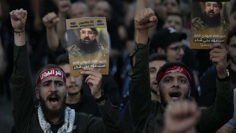 Hezbollah supporters shout slogans and hold up portraits that show the top commander Fouad Shukur, who was killed by an Israeli airstrike during his funeral procession in a Beirut, Lebanon suburb, Aug. 1, 2024. (AP Photo/Hussein Malla, file)