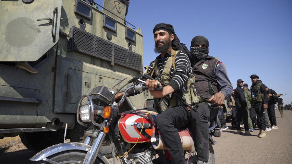 Two fighters from the Sunni Bedouin clans ride their motorcycle as they pass by Syrian government security forces where clashes erupted between Druze militias and Sunni Bedouin clans, southern Syria, July 14, 2025. (AP Photo/Malek Khattab)