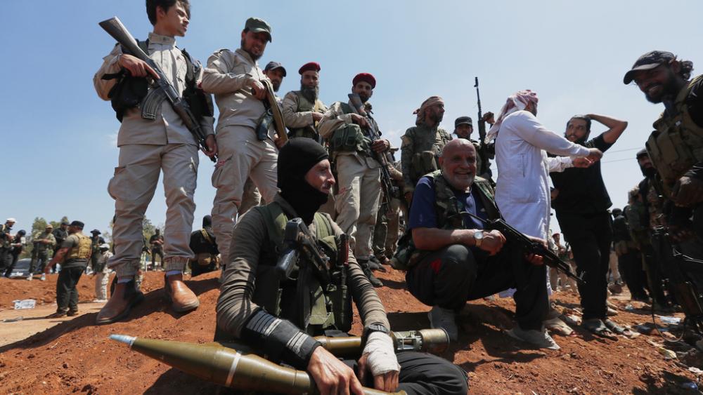 Syrian government security forces block Bedouin fighters, background, from entering Sweida province, in Busra al-Harir village, southern Syria, Sunday, July 20, 2025. (AP Photo/Omar Sanadik