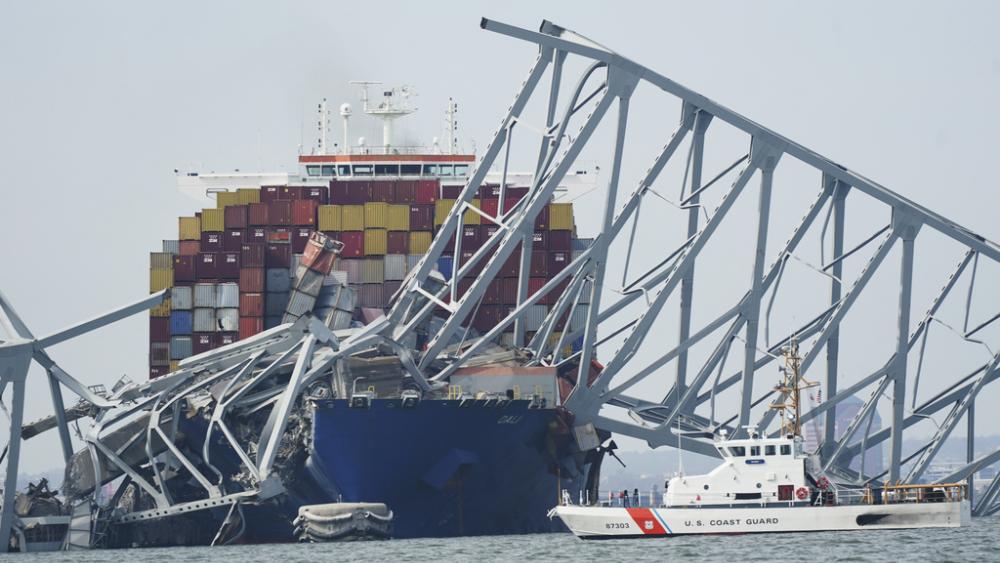 A Coast Guard cutter passes a cargo ship that is stuck under the part of the structure of the Francis Scott Key Bridge after the ship his the bridge Tuesday, March 26, 2024, in Baltimore, Md. (AP Photo/Steve Helber)