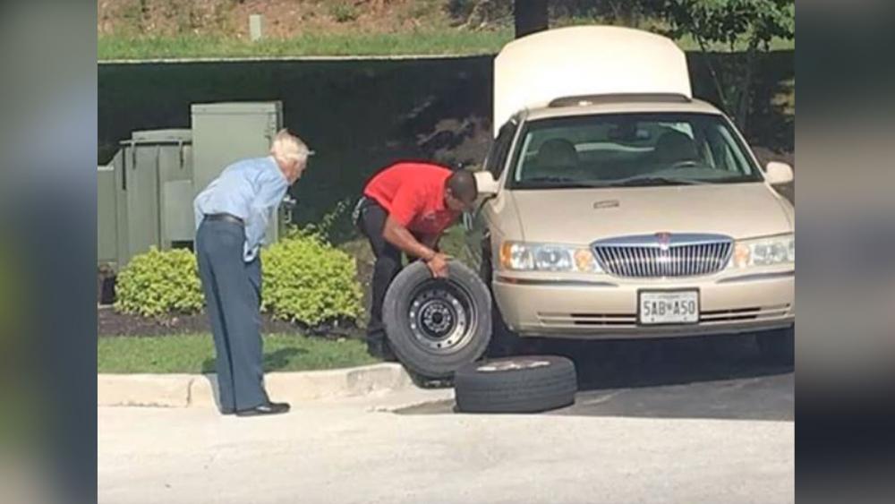 Chick-fil-A Manager Daryl Howard is seen helping Mr. Lee, a 96-year-old World War II veteran, change a tire. (Screenshot credit: Rudy Somoza/YouTube) 