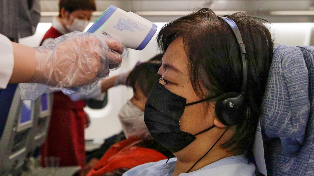Stewardesses take temperatures of passengers as a preventive measure for the coronavirus on an Air China flight from Melbourne to Beijing (AP photo)