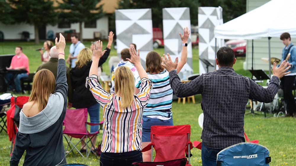 Church members raise their hands as Pastor Greg Payton leads a live outdoor service at The Rock Church in Laurel, Mont., Sunday, April 26, 2020. (Larry Mayer/The Billings Gazette via AP)