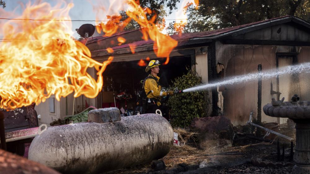 Firefighter Nolan Graham sprays water around a scorched garage as the Boyles fire burns in Clearlake, Calif., on Sunday, Sept. 8, 2024. (AP Photo/Noah Berger)