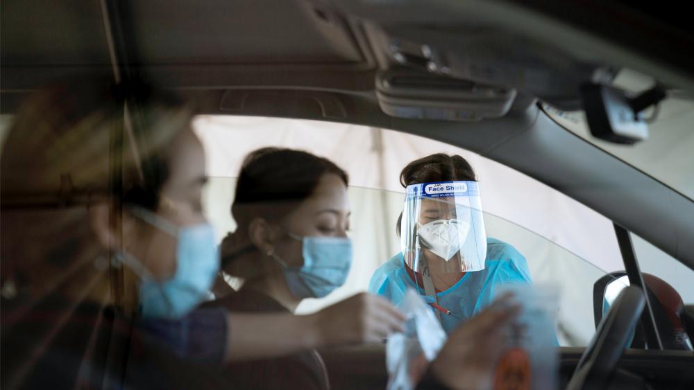 Medical assistant Linh Nguyen assists two women with COVID-19 testing at a testing site set up at the OC Fairgrounds in Costa Mesa, Calif., Nov. 16, 2020. (AP Photo/Jae C. Hong)
