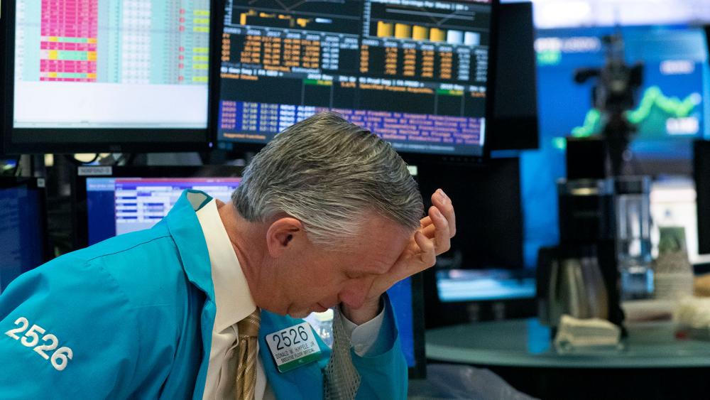A trader holds his hand to his head after trading was halted at the New York Stock Exchange, Wednesday, March 18, 2020, in New York. (AP Photo/Mark Lennihan)