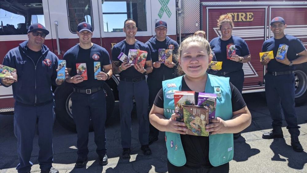 This undated photo provided by Girl Scouts of New Mexico Trails shows a scout donating cookies to firefighters in Rio Rancho, New Mexico, as part of the Hometown Heroes program. (Girl Scouts of New Mexico Trails via AP)