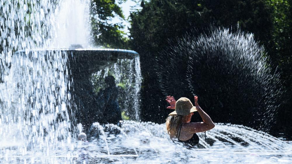 A woman cools off on Albertplatz at the water fountains of the &quot;Still Water&quot; and &quot;Stormy Waves&quot; fountains in Dresden, Germany, July 19, 2022. (Robert Michael/dpa via AP)