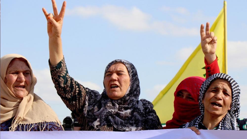 Kurdish women flash victory signs and shout to protest against the expected Turkish military invasion on their areas, at the Syrian-Turkish border, in Ras al-Ayn, Syria, Oct. 7, 2019. (AP Photo)