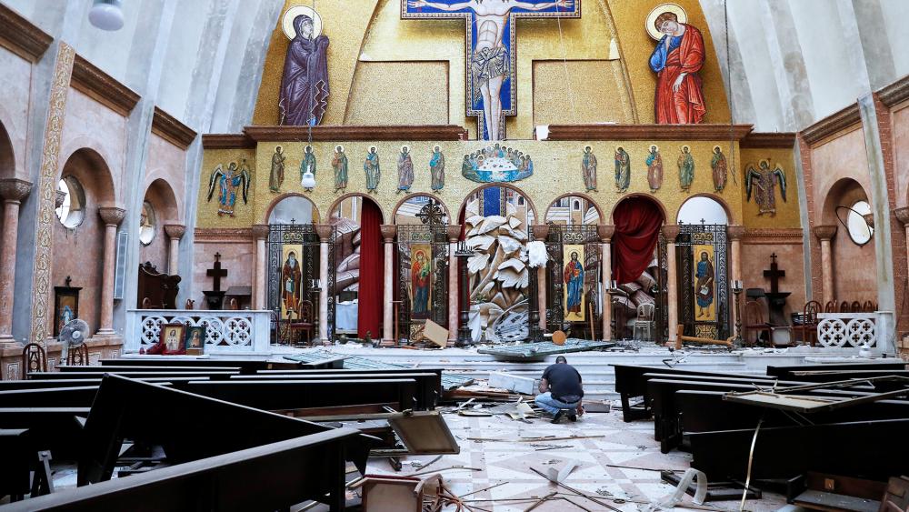 A man removes religious icons from the floor of a damaged church a day after an explosion hit the seaport of Beirut, Lebanon, Wednesday, Aug. 5, 2020. 