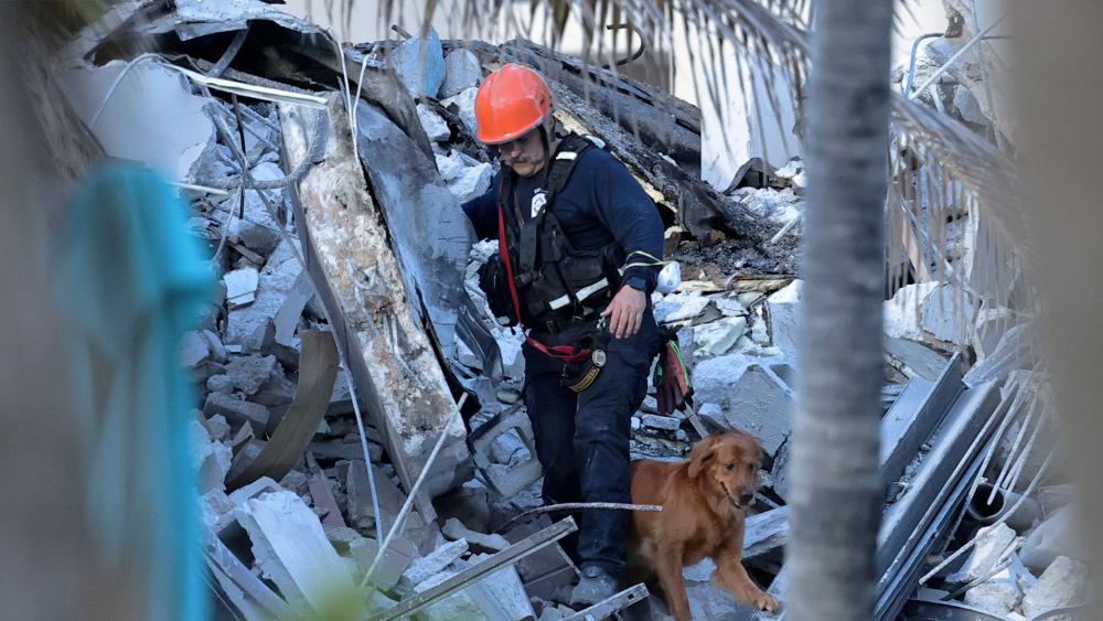 Fire rescue personnel conduct a search and rescue with dogs through the rubble of the Champlain Towers South Condo after the multistory building partially collapsed in Surfside, Fla., Thursday, June 24, 2021. (David Santiago/Miami Herald via AP)