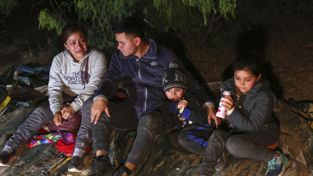 A family from Honduras sits on the ground after they were smuggled on an inflatable raft across the Rio Grande, in Roma, Texas Saturday, March 27, 2021.<br>
