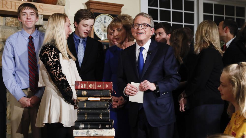 Ohio&#039;s 70th Governor Mike DeWine prepares to take oath of office on a stack of nine Bibles. (AP Photo/John Minchillo, Pool)