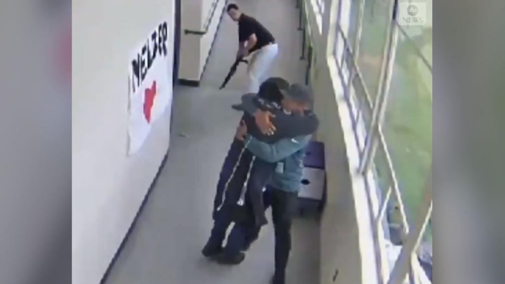 In this screenshot from school surveillance video, a Portland, Oregon high school coach embraces a student he has just disarmed. (Image credit: ABC News)