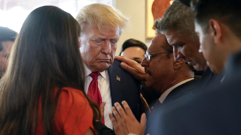 Former President Donald Trump prays with pastor Mario Bramnick, third from right, at a restaurant on June 13, 2023, in Miami. Trump appeared in federal court Tuesday on dozens of felony charges regarding classified documents. (AP Photo/Alex Brandon)