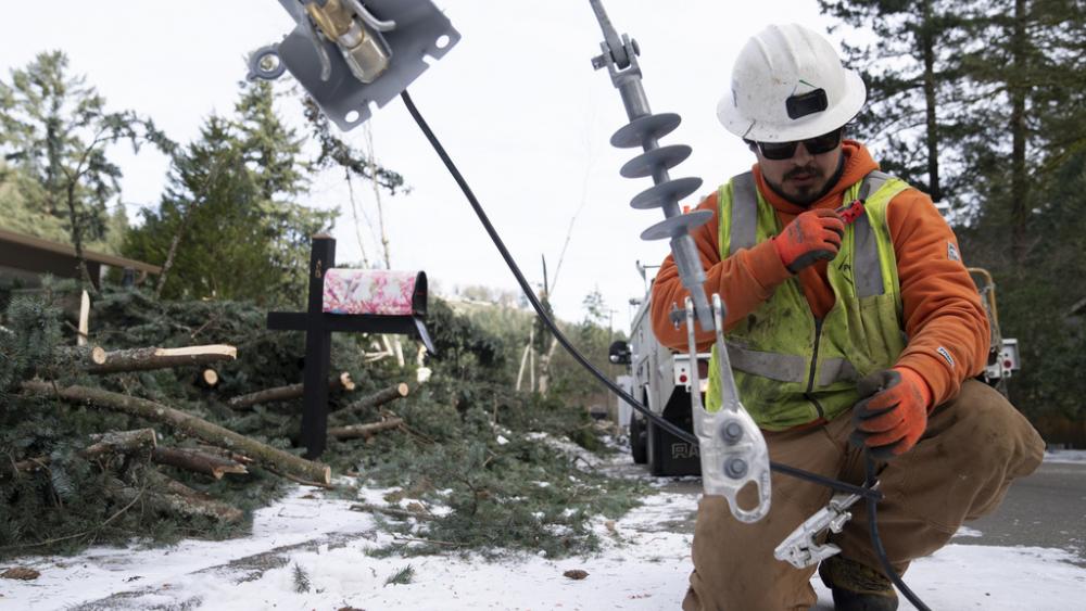 A worker from PGE works to install a new power line as crews work on restoring power to the area after a storm on Tuesday, Jan. 16, 2024, in Lake Oswego, Ore. (AP Photo/Jenny Kane)