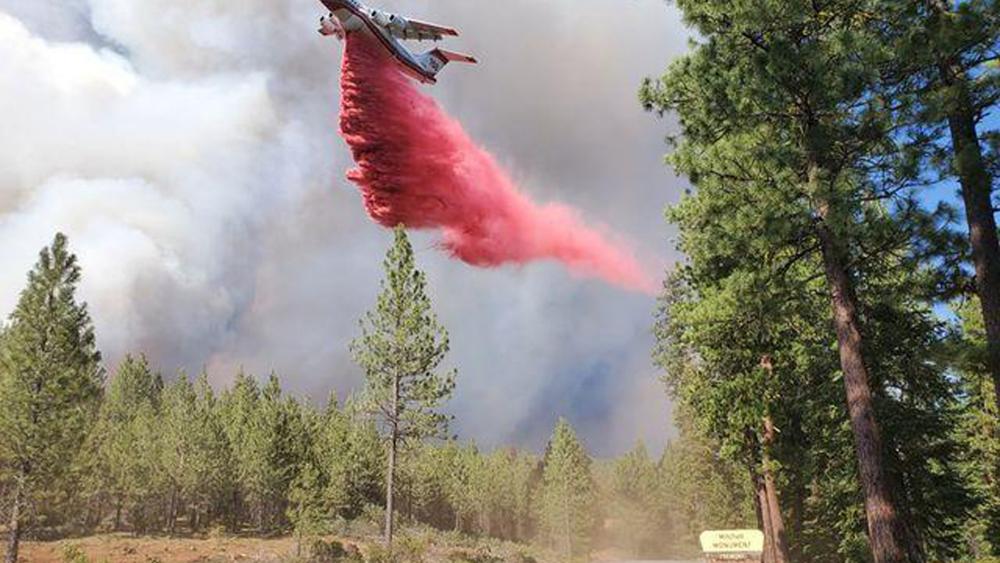 In this photo provided by the Bootleg Fire Incident Command, a tanker drops retardant over the Mitchell Monument area at the Bootleg Fire in southern Oregon on Saturday, July 17, 2021.  (Bootleg Fire Incident Command via AP)