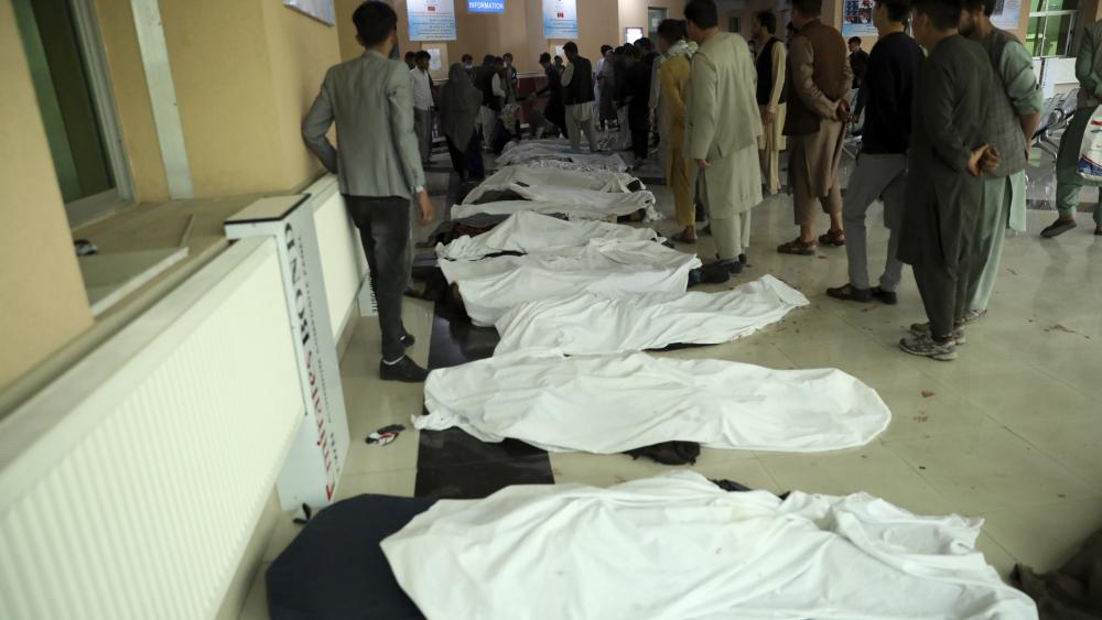 In this May 8, 2021 file photo, Afghan men try to identify the dead bodies at a hospital after a bomb explosion near a school west of Kabul, Afghanistan. (AP Photo/Rahmat Gul, File)