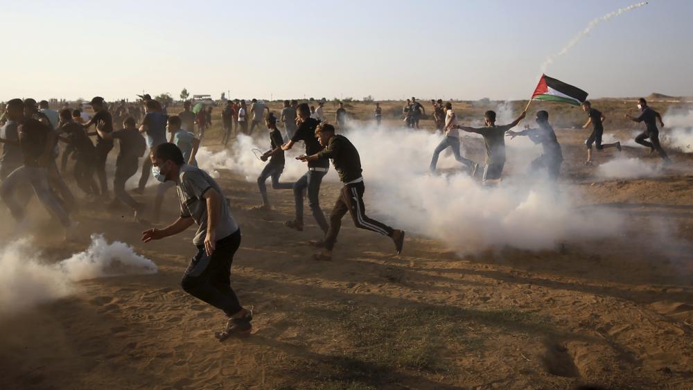 Protesters run and take cover from teargas fired by Israeli troops near the fence of Gaza Strip border with Israel during a protest east of Khan Younis, southern Gaza Strip, Wednesday, Aug. 25, 2021. (AP Photo/Abdel Kareem Hana)