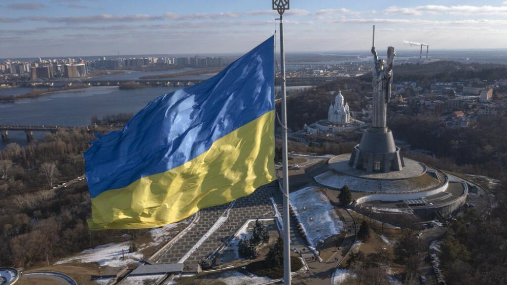 A view of Ukraine's national flag waves above the capital with the Motherland Monument on the right, in Kyiv Sunday, Feb. 13, 2022. (AP Photo/Efrem Lukatsky)