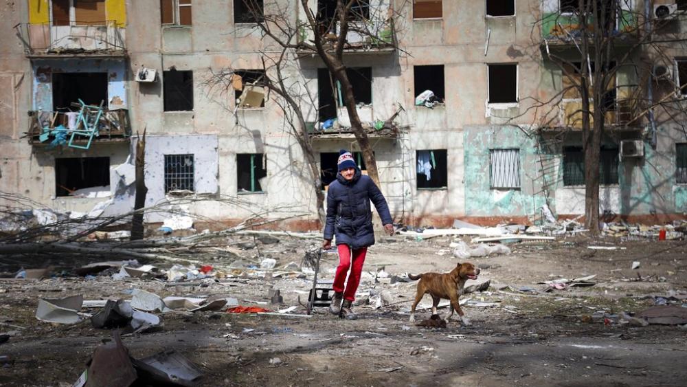A man walks with his dog near an apartment building a damaged by shelling from fighting on the outskirts of Mariupol, Ukraine. (AP Photo/Alexei Alexandrov)  