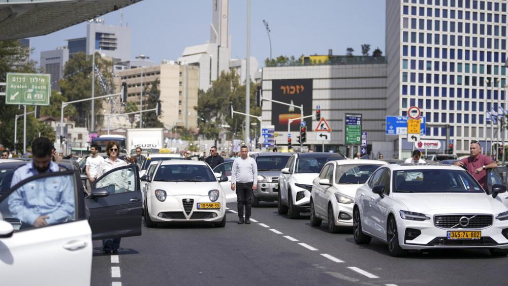 Israelis stand still next to their cars on a main road as a two-minute siren sounds in memory of victims of the Holocaust in Tel Aviv, Israel, Thursday, April 28, 2022. (AP Photo/Ariel Schalit)