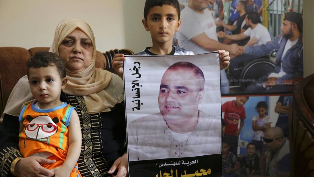 Amal el-Halabi holds her grandson Fares while her grandson Amro, 7, holds a picture of his father Mohammed el-Halabi, Gaza director of the international charity World Vision. (AP Photo)