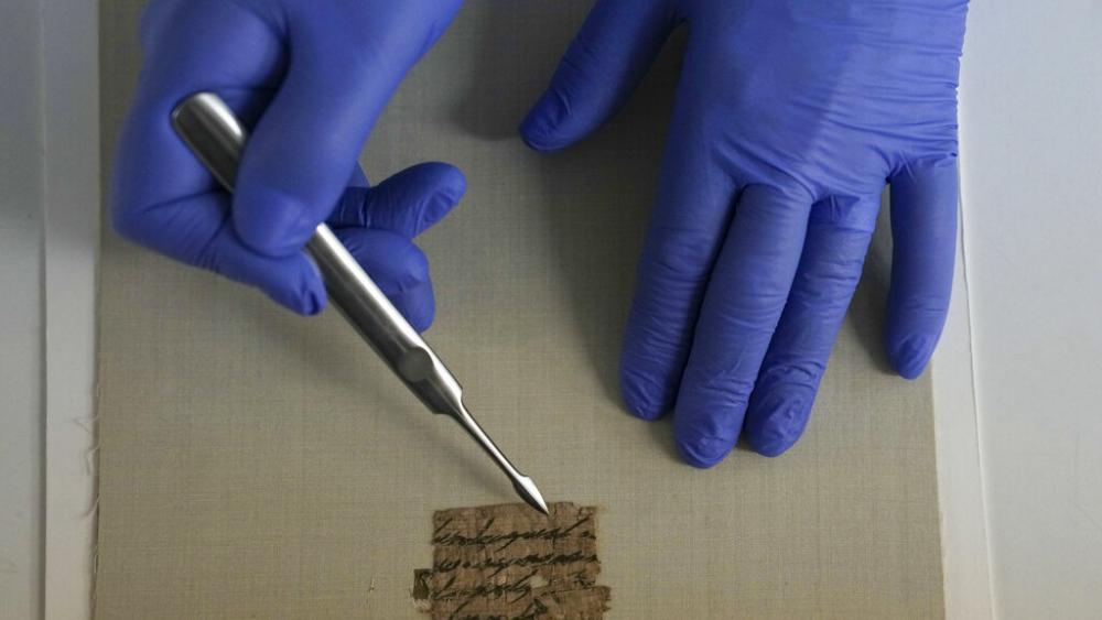 Israeli Antiquities Authority&#039;s official conservator, Tanya Bitler, shows a papyrus fragment at their lab inside the Israel Museum in Jerusalem, Wednesday, Sept. 7, 2022. (AP Photo)