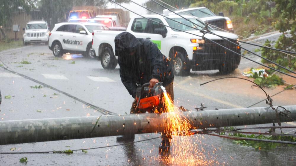 A worker cuts an electricity pole that was downed by Hurricane Fiona as it blocks a road in Cayey, Puerto Rico, Sunday, September 18, 2022. (AP Photo/Stephanie Rojas)