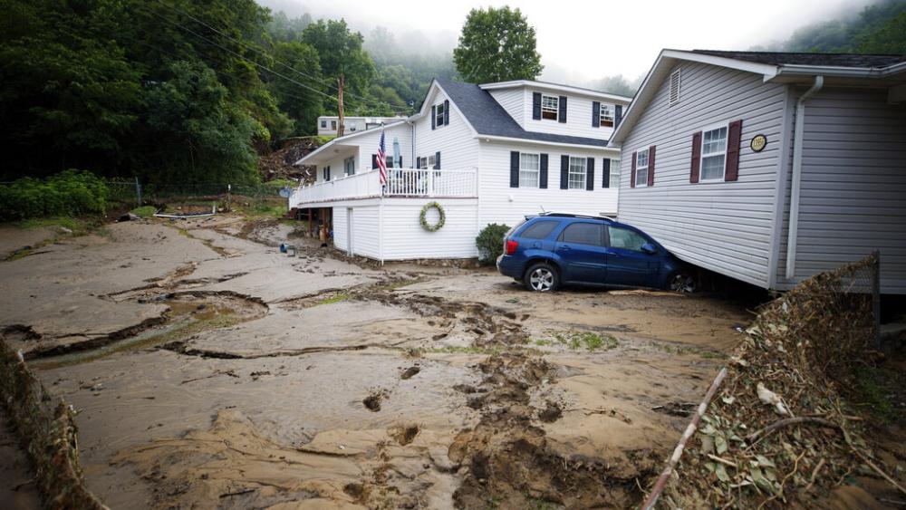 A house that was moved off of its foundation following a flash flood rests on top of a vehicle, Thursday, July 14, 2022 in Whitewood, Va. (AP Photo/Michael Clubb)