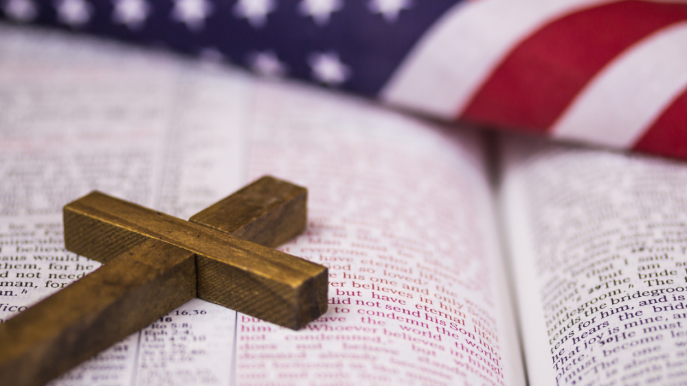 American flag with a Bible in front and a cross on top of the Bible