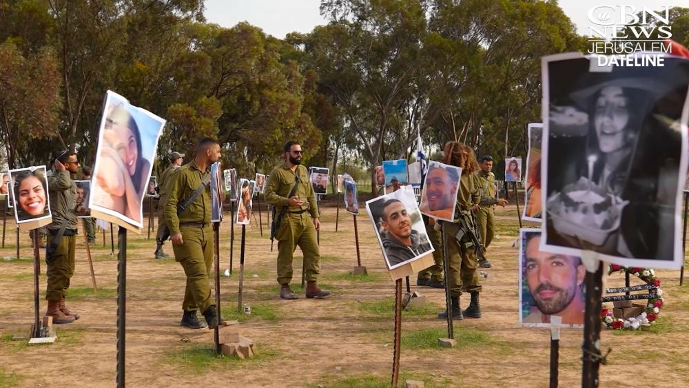 Israeli soldiers walk among photos of people slain and taken captive at the Nova Music Festival. Photo Credit: CBN News.