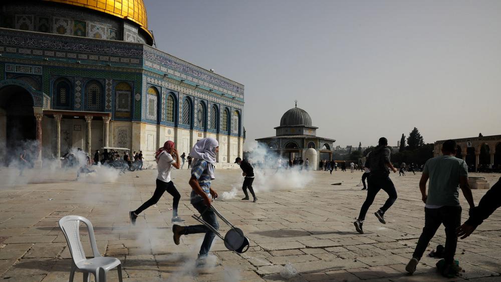 Palestinians run away from tear gas during clashes with Israeli security forces at the Al Aqsa Mosque compound in Jerusalem&#039;s Old City Monday, May 10, 202. (AP Photo/Mahmoud Illean)