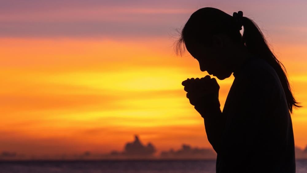 silhouette of a woman crying and praying