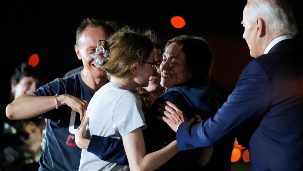 President Biden interrupts Alsu Kurmasheva, who is hugging her daughters Bibi Butorin, Miriam Butorin and husband Pavel Butorin, after the prisoner swap with Russia, Aug. 1, 2024. (AP Photo/Alex Brandon)